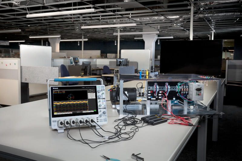 A 4 Series B MSO oscilloscope with three voltage probes, three current probes, and three-phase analysis software, showing pulse-width modulated waveforms