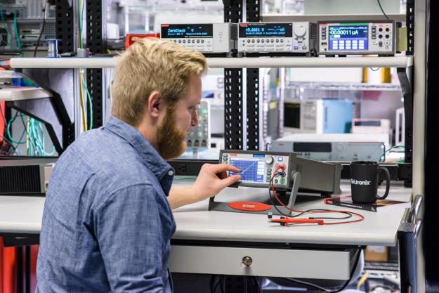 An engineer using the Keithley touchscreen interface on a source measure unit (SMU).