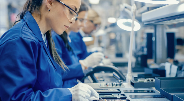 Two semiconductor assembly line workers in blue lab coats building with various electronic components
