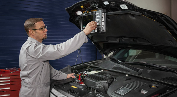Engineer making measurements on automotive engine sensors